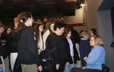 Angelika odpowiada na pytania nauczycielki, dzieci stoją wok&oacute;ł niej po autograf