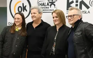 Aktorzy od lewej Piotr Polk oraz Piotr Szwedes na ściance zdjęciowej z uczestniczkami spotkania.