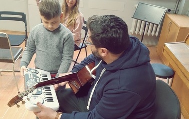 Instruktor zajęć tłumaczy uchwyty gitarowe