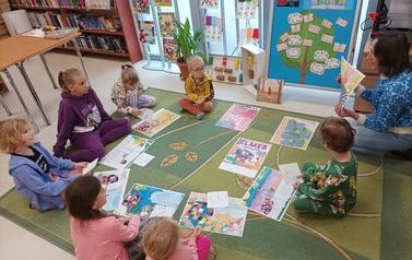 Bibliotekarka czyta dzieciom na dywanie bajkę