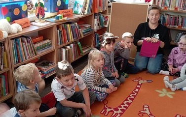 Dzieci siedzą na dywanie i słuchają opowiadań 