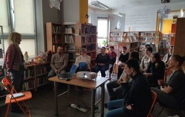 Prowadząca opowiada o historii lalek, w tle uczestniczy spotkania